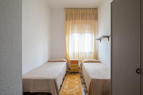 two beds in a small room with a window at Casa Hibiscus Villasimius in Villasimius