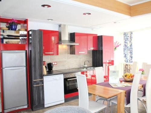 a kitchen with red cabinets and a table with white chairs at Stad Vakantiehuis Vulkaneifel in Daun