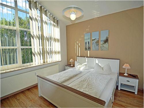 um quarto com uma grande cama branca e janelas em Evening sun Juliusruh em Juliusruh