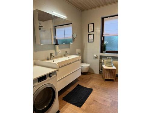 a bathroom with a washing machine and a sink at Lovely apartment near the water in Weilburg
