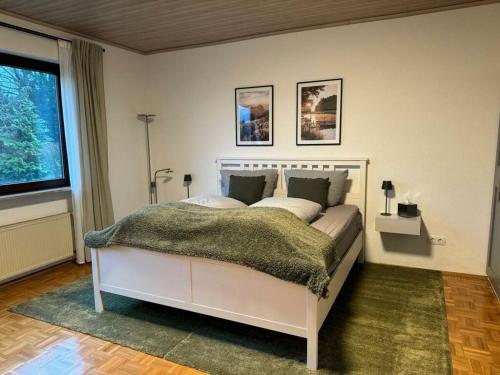 a bedroom with a white bed with a green blanket at Lovely apartment near the water in Weilburg