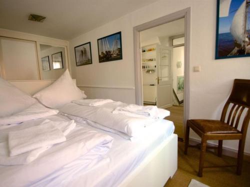 a white bed in a room with a chair at On the Trave Comfortable holiday residence in Travemünde