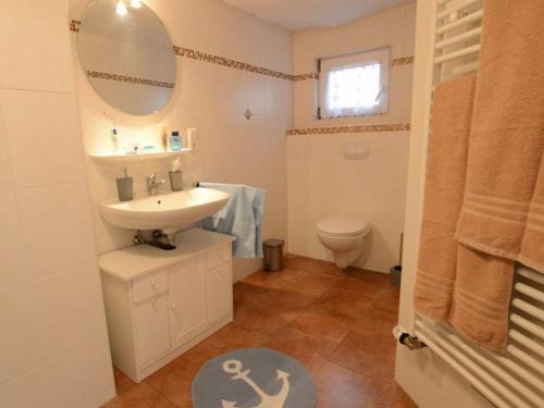 een badkamer met een wastafel, een toilet en een spiegel bij Farmhouse Comfortable holiday residence in Norddeich