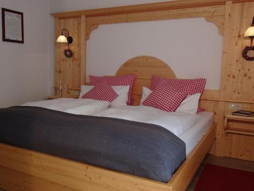 a bedroom with a wooden bed with red and white pillows at 1 - House Rosenegger in Staudach-Egerndach