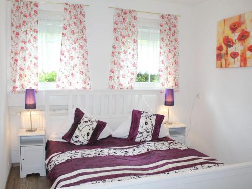 um quarto com uma cama branca e 2 janelas em Vulkaneifel Comfortable holiday residence em Daun