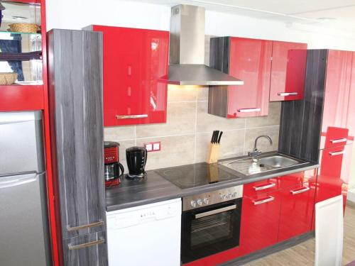 a kitchen with red cabinets and a sink at Vulkaneifel Comfortable holiday residence in Daun