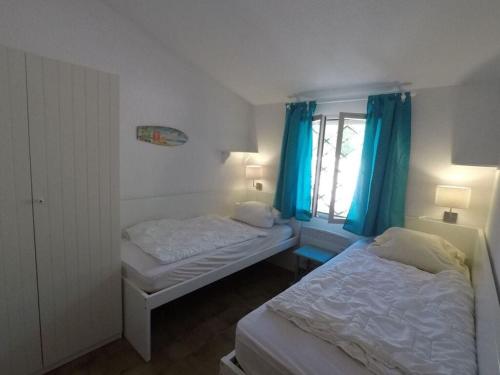 une chambre avec deux lits et une fenêtre avec des rideaux bleus dans l'établissement Maison 58 Cavalaire Comfortable holiday residence, à Cavalaire-sur-Mer