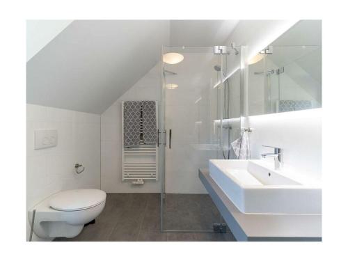 a white bathroom with a toilet and a sink at Meerzeit Comfortable holiday residence in Juliusruh