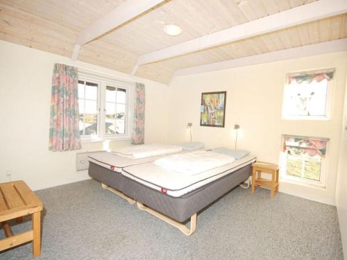 ein Schlafzimmer mit einem Bett und zwei Fenstern in der Unterkunft Lynglihus Ly92 in Hvide Sande