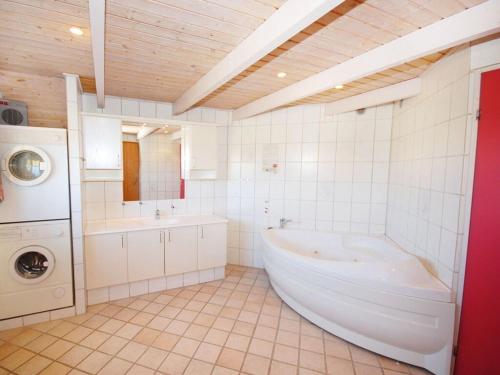 ein Badezimmer mit einer Badewanne und einer Waschmaschine in der Unterkunft Lynglihus Ly92 in Hvide Sande