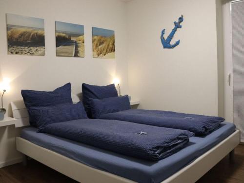 a bed with blue pillows in a room at Anchorage Comfortable holiday residence in Fedderwardersiel