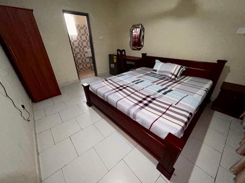 um quarto com uma cama e piso em azulejo branco em Jessie Hotel em Apenkwa