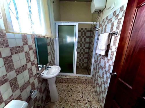 uma casa de banho com um lavatório e um chuveiro com um WC. em Jessie Hotel em Apenkwa