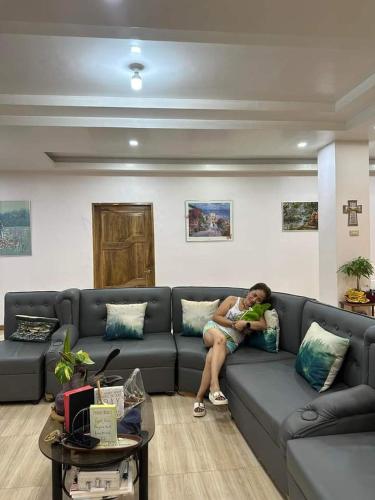 una mujer sentada en un sofá sosteniendo un bebé en RosePlace Guesthouse en Tangub