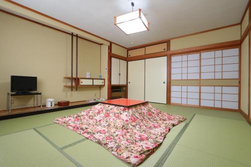 a room with a table on the floor with a flower rug at Ryokan Nakaya in Muraoka