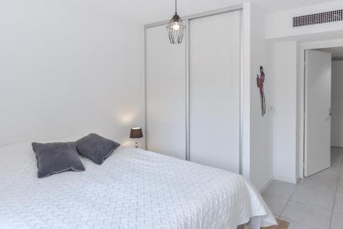une chambre blanche avec un lit blanc avec deux oreillers dans l'établissement Modern apartment with swimming pool, à Cannes