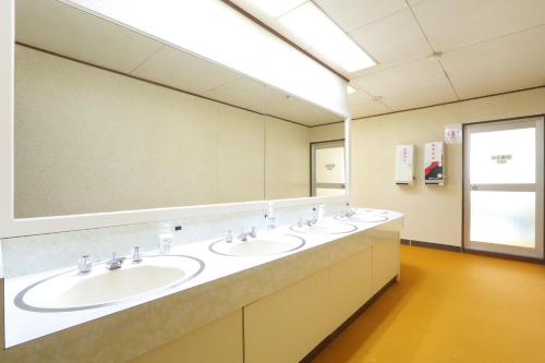 La salle de bains est pourvue de 3 lavabos et d'un grand miroir. dans l'établissement Ryokan Nakaya, à Muraoka