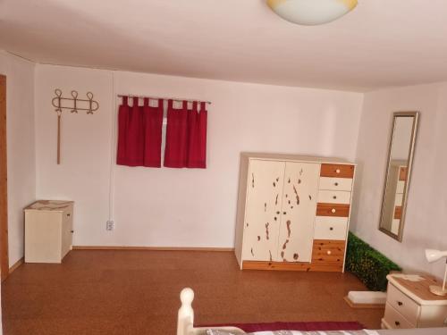 an empty living room with a dresser and red curtains at Ferienwohnung Kefeder in Lochenhaus