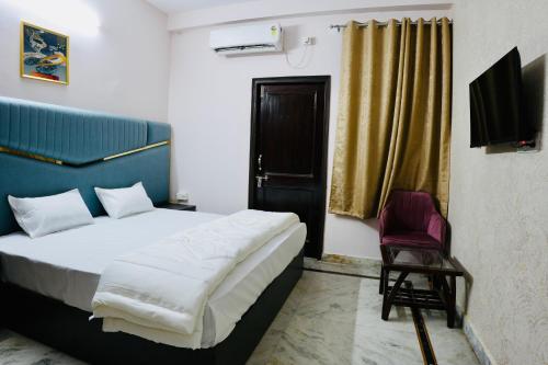 a bedroom with a bed and a chair and a television at BLISS STAYS in Rishīkesh