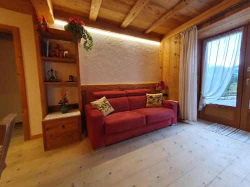 a living room with a red couch and a window at Daniela Apartment in Cortina dʼAmpezzo