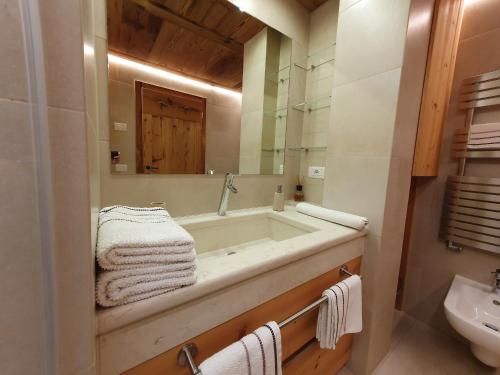 een badkamer met een bad, een wastafel en een spiegel bij Daniela Apartment in Cortina dʼAmpezzo
