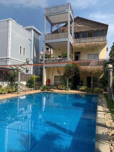 YASSS LGBTQ Guesthouse Siem Reap في سيام ريب: مسبح ازرق كبير امام مبنى