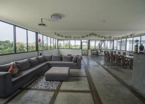 una gran sala de estar con sofá, mesas y ventanas. en YASSS LGBTQ Guesthouse Siem Reap en Siem Reap