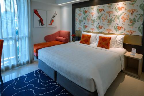 a hotel room with a large bed and a chair at Hotel Clover Asoke - SHA Extra Plus in Bangkok