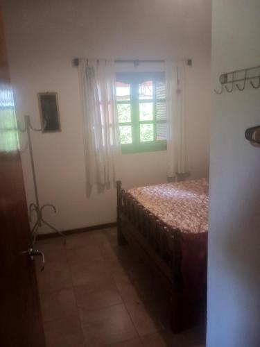 1 dormitorio con cama y ventana en cabaña La Retama en Villa Yacanto