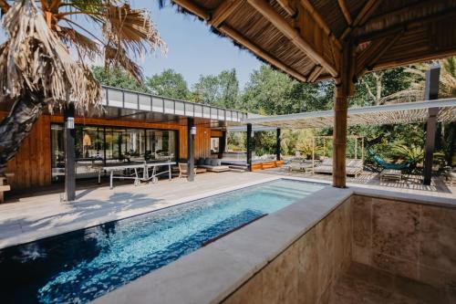 une piscine extérieure avec une maison avec patio dans l'établissement Villa PAPAGAYO, piscine chauffée, jacuzzi & sauna, à Pessac