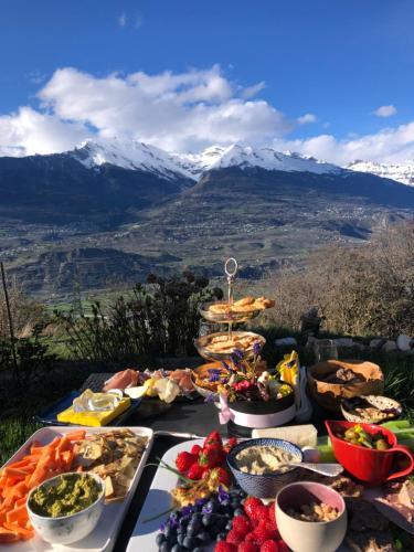 a table full of food with mountains in the background at Domaine Bellevie BnB in Vex