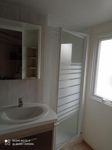 a bathroom with a sink and a mirror and a window at Mobil-home in La Bernerie-en-Retz