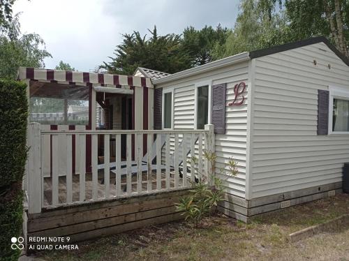 a white house with a gate and a fence at Mobil-home in La Bernerie-en-Retz