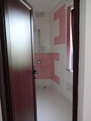 a bathroom with a tub and a shower with pink tiles at Guest House Nocturno in Berkovitsa