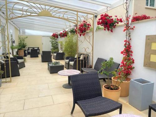 a patio with tables and chairs and flowers on the wall at Hôtel Le Méditerranée in Hyères