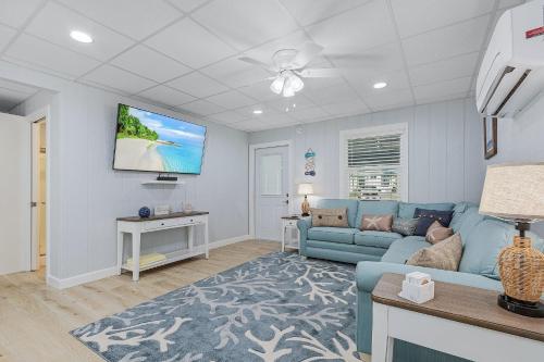 Una sala de estar con un sofá azul y un televisor de pantalla plana. en Amber Jack - 210 Ostego Dr home, en Fort Myers Beach
