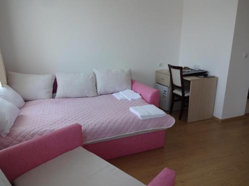 a living room with a pink couch and a desk at Guest House Nocturno in Berkovitsa