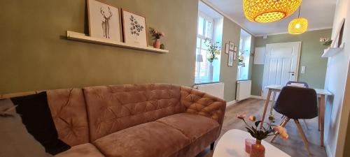 - un salon avec un canapé brun et une table dans l'établissement Ferienwohnung am Bibelgarten Sophia, à Werlte