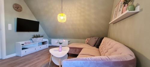 - un salon avec un canapé et une télévision dans l'établissement Ferienwohnung am Bibelgarten Sophia, à Werlte