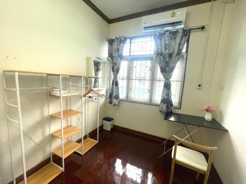 um quarto com uma secretária e uma janela em 2B Cozy Hostel ตรัง em Trang