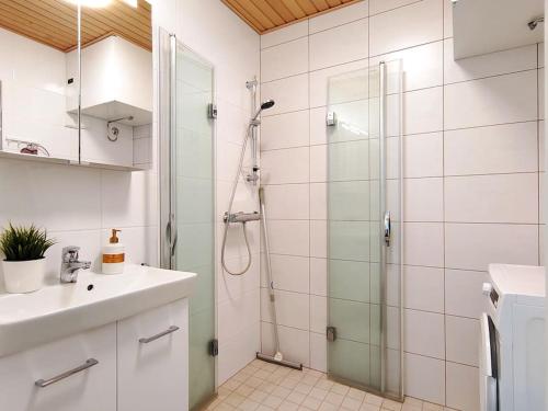 a white bathroom with a shower and a sink at Huoneisto Puusatama, Joensuu in Joensuu