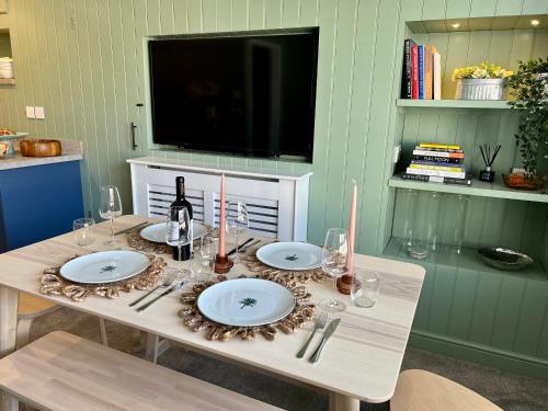 a table with plates and wine glasses and a television at Luxury townhouse - your perfect retreat in Hertford in Hertford