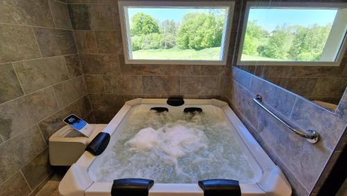 a bathroom with a bath tub with a cell phone in it at Maison calme avec Spa et beau paysage, à 40mn des plages in Saint-Jean-de-Livet