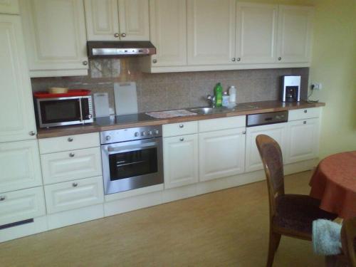 una cucina con armadietti bianchi, piano cottura e tavolo di Koch 2 Comfortable holiday residence ad Artstetten