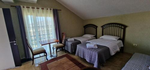 - une chambre avec 2 lits, une table et une fenêtre dans l'établissement Sunrise Lindita, à Pukë