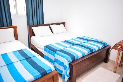 a bedroom with two beds with blue and white sheets at The Emerald Guest House & Villa in Unawatuna