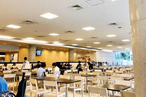 a cafeteria with tables and chairs and people working at 渋谷5分のダブルベット2台の40平米東京大学徒歩5分のアパート in Tokyo