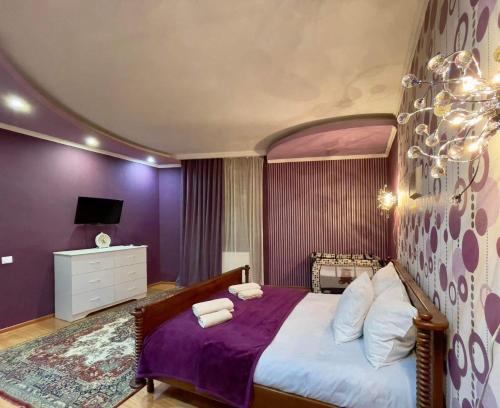 - une chambre avec un grand lit aux murs violets dans l'établissement Brothers, à Tbilissi