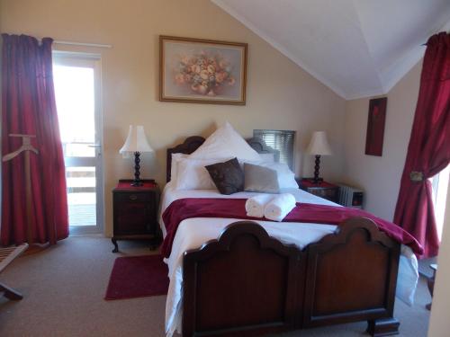 a bedroom with a large bed with red curtains at Avondsrus Guesthouse in Bettyʼs Bay