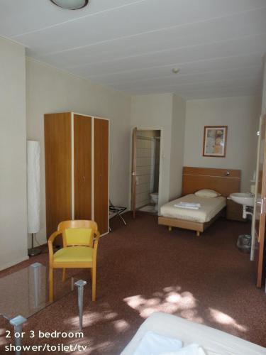 a room with a bedroom with a bed and a chair at Hotel 't Anker in Leeuwarden